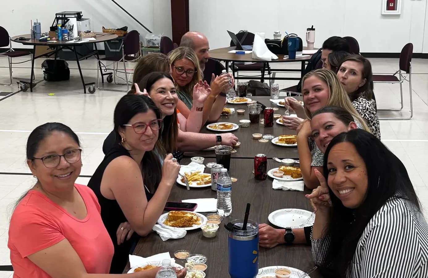 Eleven Virtual Horizons teachers and staff seated along a long table at onboarding training, turned toward the camera and smiling.