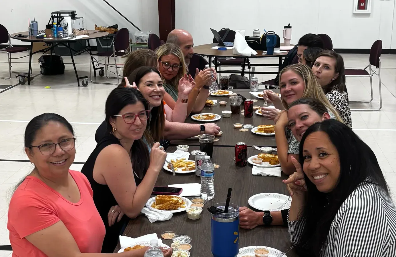 Eleven Virtual Horizons teachers and staff seated along a long table at onboarding training, turned toward the camera and smiling.