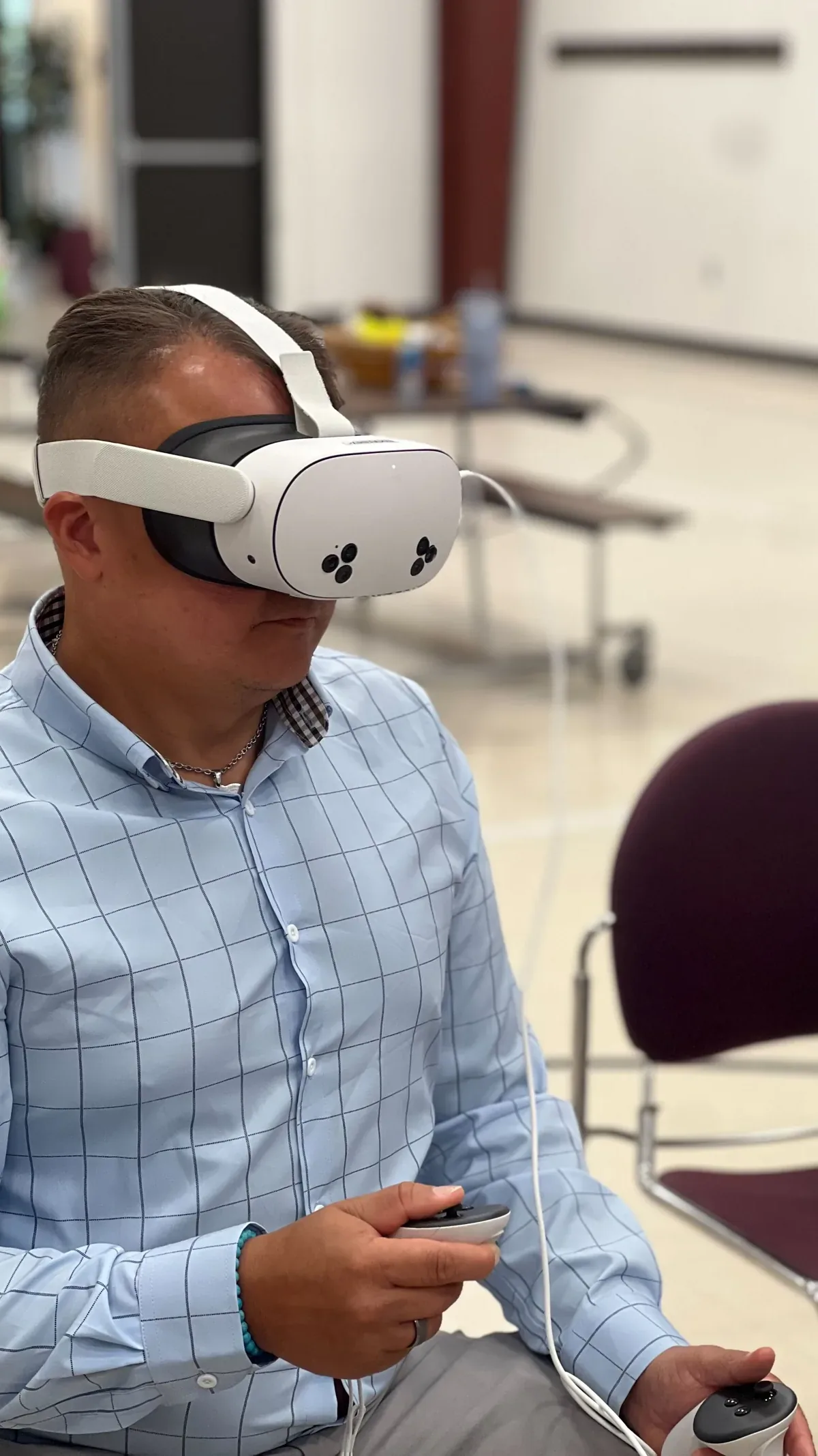 A Virtual Horizons team member seated in a Quest 3S headset during onboarding training, a controller in each hand.