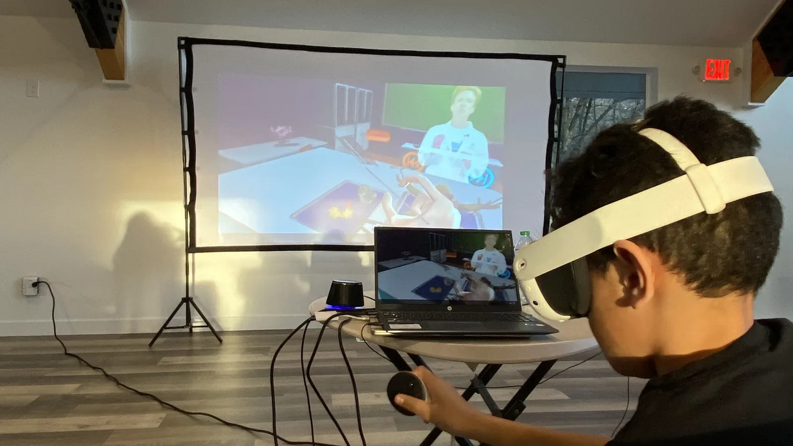 A high-school student wearing a VR headset participates in a lesson with a laptop nearby.