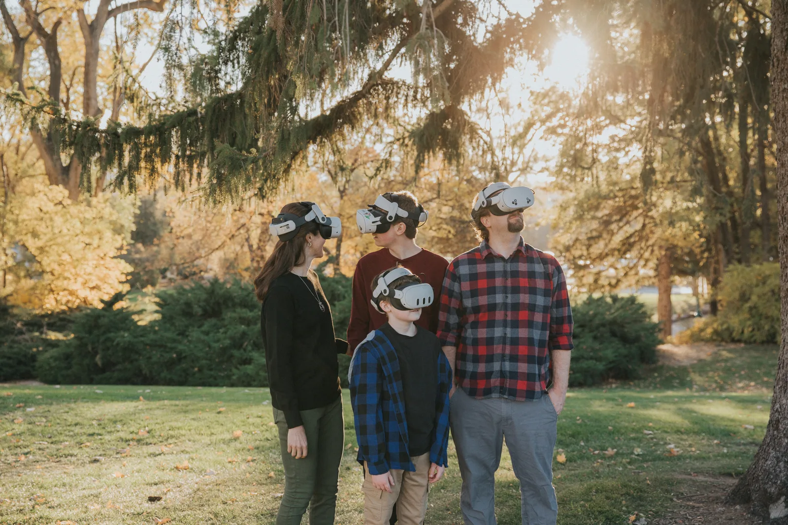 The Strong family outdoors at golden hour, all four in VR headsets, seen in profile looking upward.