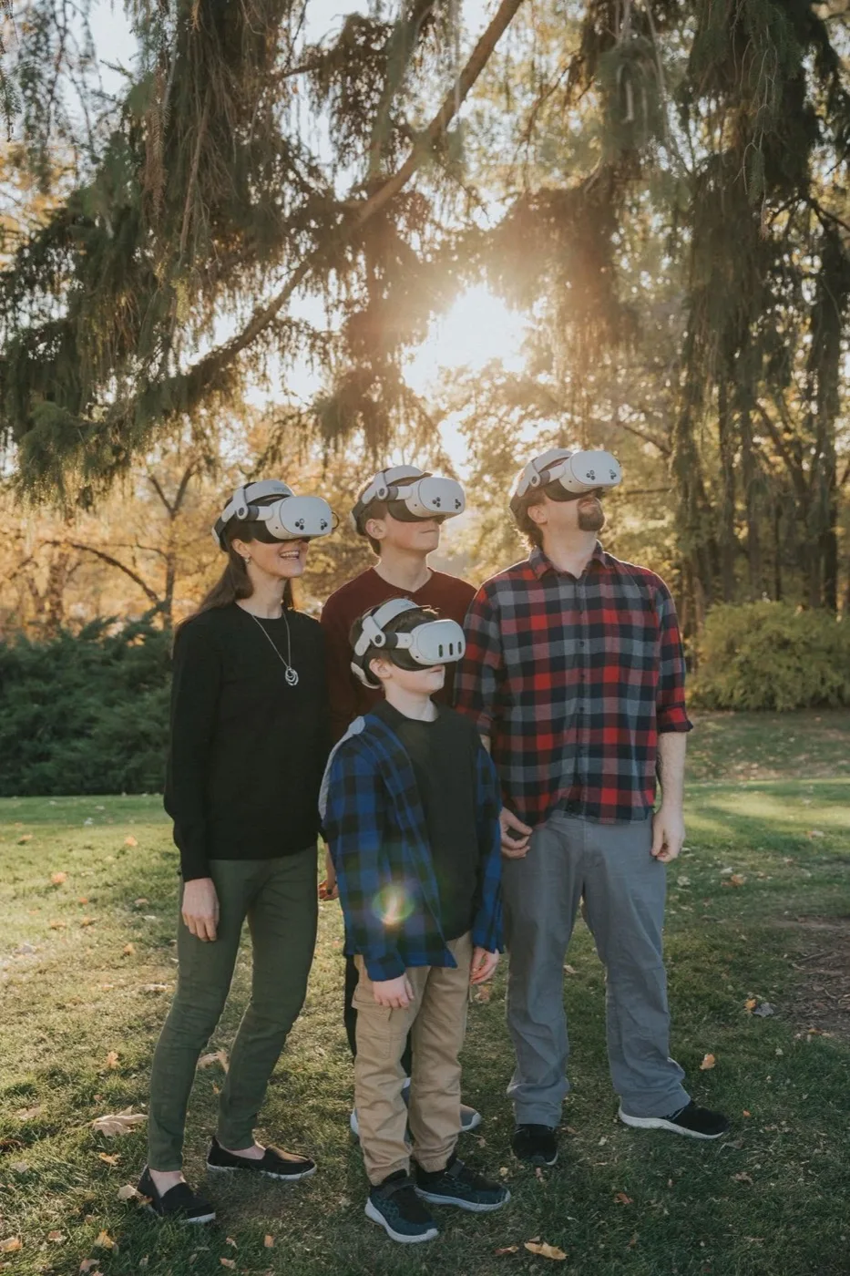 The Strong family outdoors at golden hour, all four wearing VR headsets and looking up.
