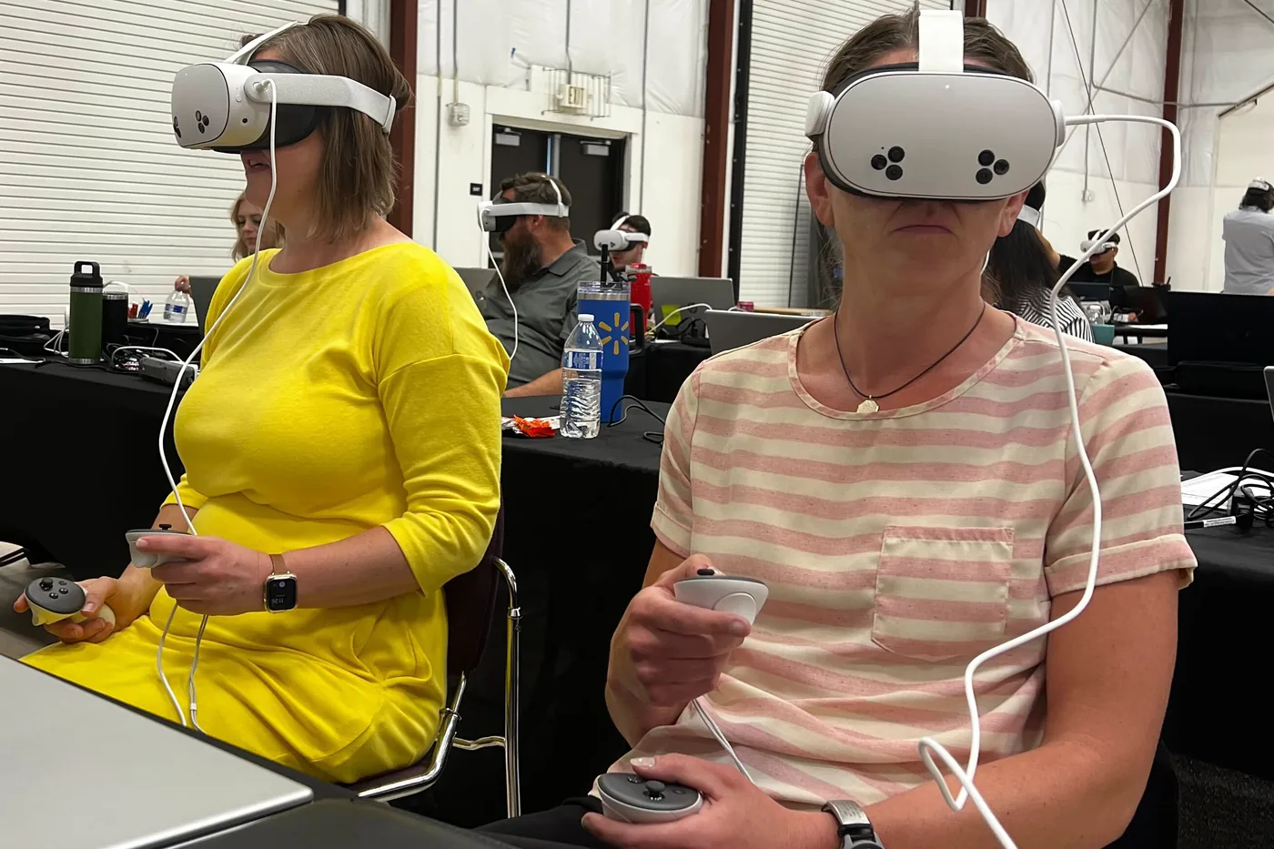 Two VHCS teachers wearing headsets and holding controllers during onboarding training.